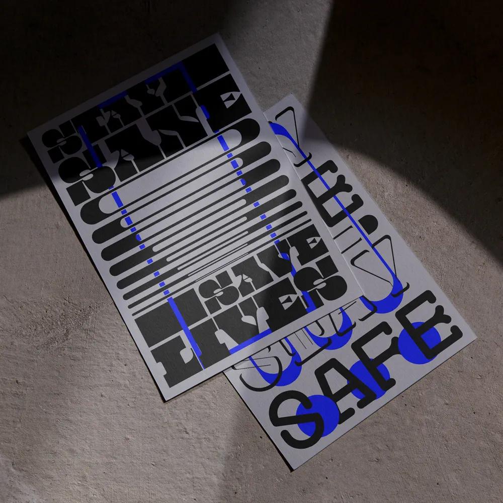 Two posters on a textured surface with bold black and blue typography, one partially covering the other casting shadows.